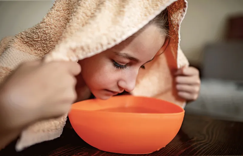 aromatherapy little girl making inhalation with steamed aromatic water from the bowl