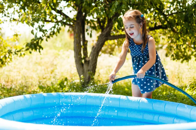 little girl pouring water into a small pool