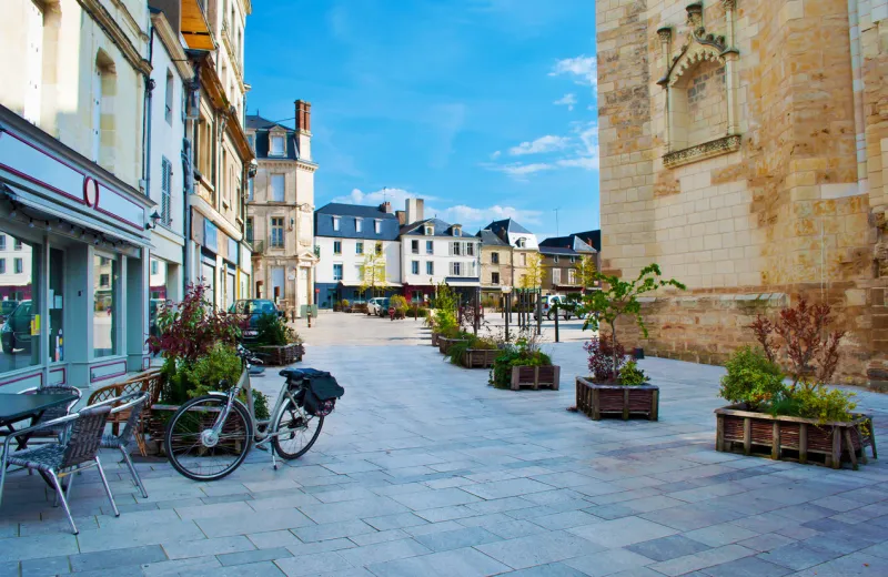 amazing solitary city center of a small town thouars, france many white and gray houses near a square, one bicycle standing near a cafe warm spring morning, vibrant blue sky, calm atmosphere