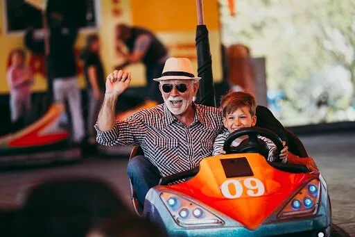 grandfather and grandson having fun and spending good quality time together in amusement park they enjoying and smiling while driving bumper car together