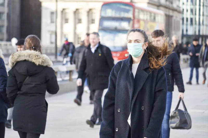 young woman wearing face mask while walking in the streets of london