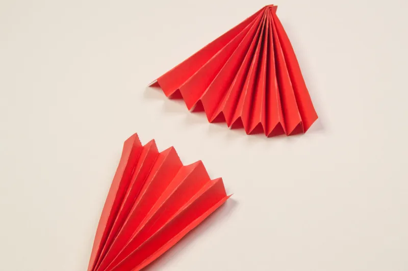 two red origami paper fans, on a white background, copy the space