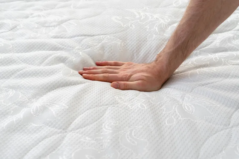 close up view of cropped hand pressing on soft orthopedic memory foam mattress man testing comfortable bed with ecologic material on hypoallergenic topper healthy sleeping and advertising concept
