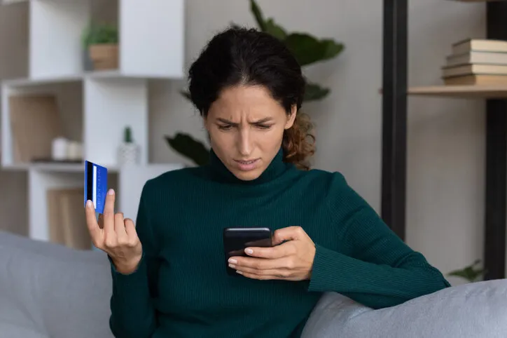 internet scam concerned young hispanic lady looking on smartphone screen having finance savings stolen from bank card as money fraud result upset nervous latin woman become online scammers victim