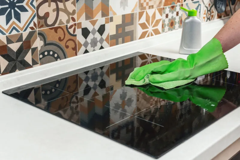 young woman hand cleaning a modern black induction hob by a rag, housework cleaning ceramic glass cooktop