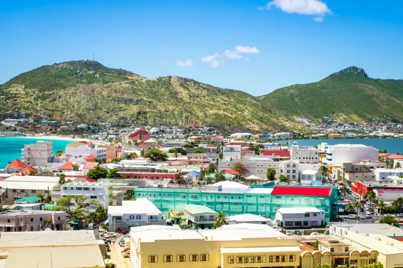 bright and colorful image of philipsburg city centre with buildings, sea and mountain blue sky