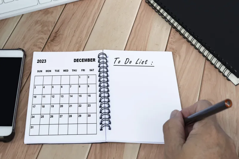 businessman hands with pen writing to do list with december 2023 calendar on notebook copy space business concept