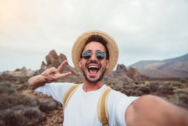 handsome hiker taking a selfie hiking a mountain using his smart
