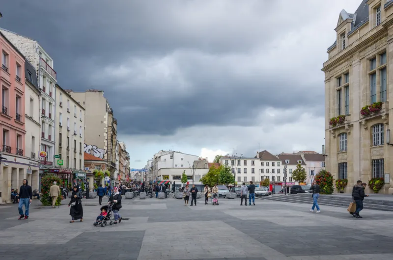saint-denis, france - september 14, 2015  people are walking in front of the city hall which overlooks place victor hugo with rue de la republique in the distance saint-denis is a suburb of the french capital, paris