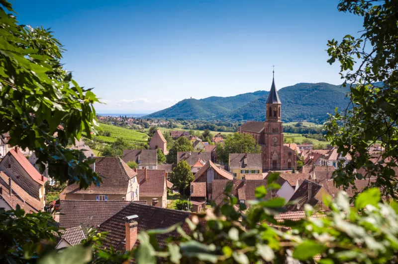 panoramic view of the typical alsatian village wihr-au-val with rooftops, church and hills in the background