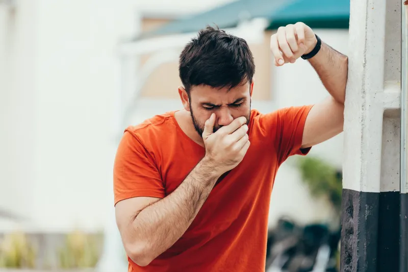 portrait of young man drunk or sick vomiting outdoors