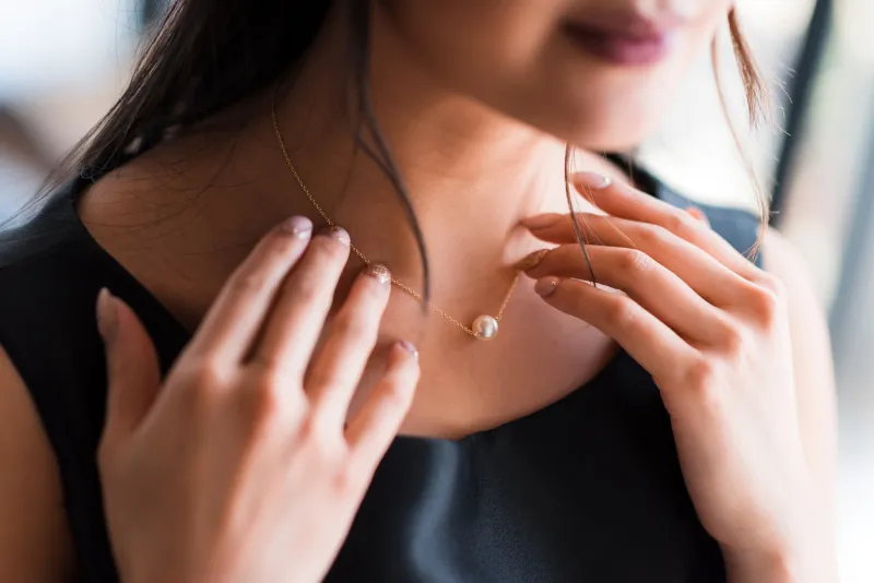 young woman trying on neck an elegant pearl jewelryget dressed for the celebration