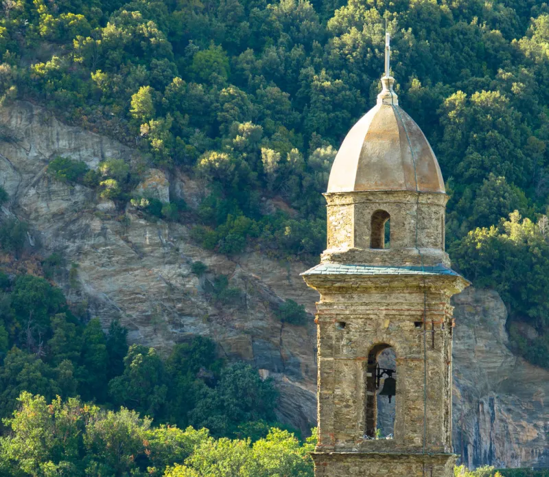 beautiful view of the bell tower from church of saint martin in patrimonio, a little town of haute corse with mountains in the background, corsica france
