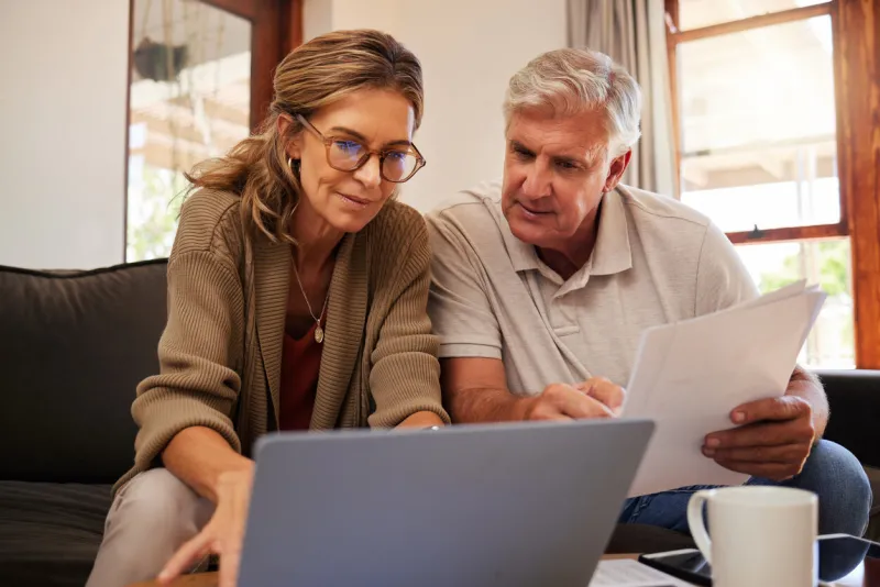 retirement couple budget, finance and investment planning, loan and paper bills with laptop technology in home mature people money, cash savings or legal insurance document report on online bank