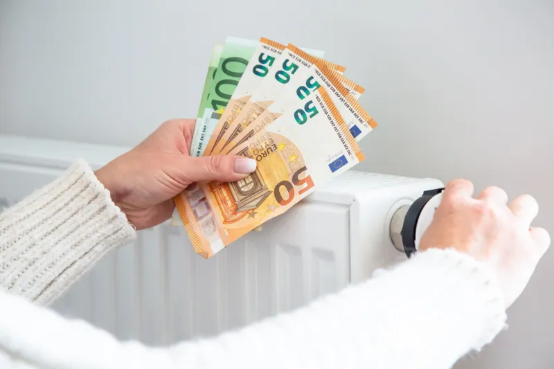 saving home heating, expensive payment for heating radiator and euro money banknotes in woman hands