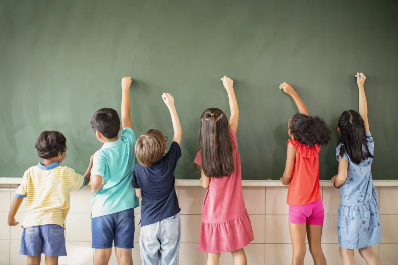 multi-ethnic group of school children drawing on the chalkboard