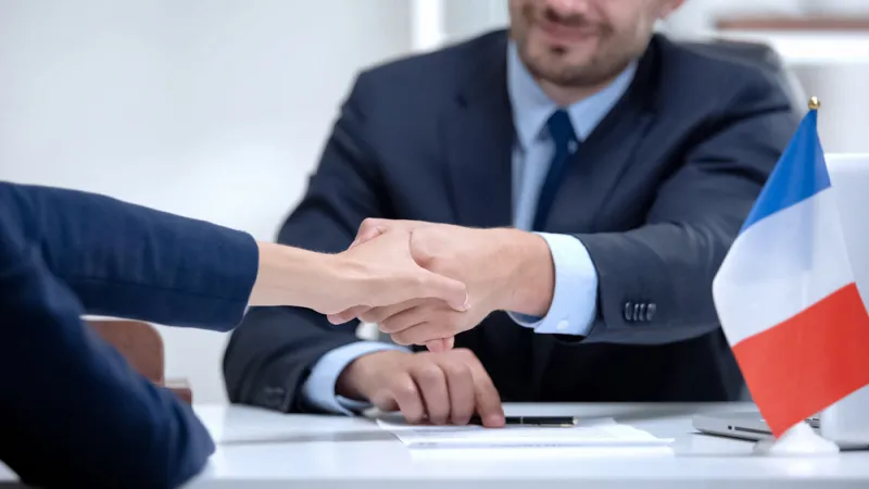 french official signing docs about state business support, shaking partner hand