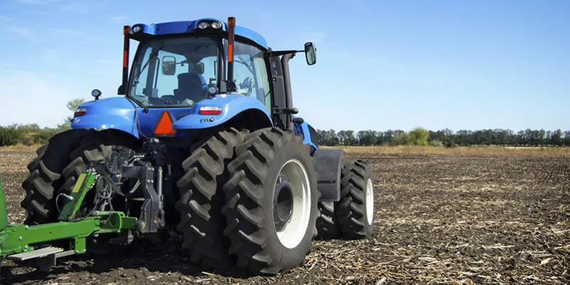the tractor wheels on the huge field, a farmer riding a tractor, a tractor working in a field, agricultural machinery in the work, tractor against the blue sky