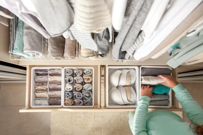unidentified neat housewife puts container with socks and pantyhose on wardrobe drawer during general cleaning by modern storage system concept of beautiful and comfortable organization