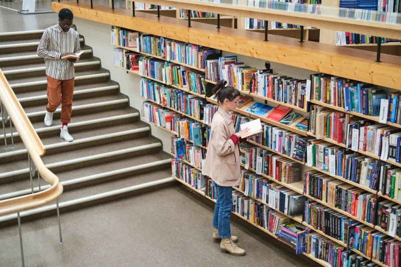 young people choosing books and reading them in the library