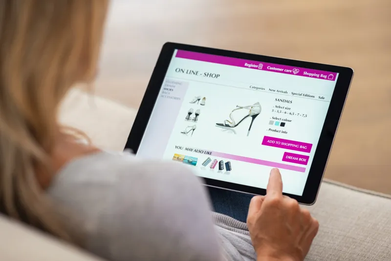 closeup of woman doing online shopping on digital tablet at home rear view of woman hand touching screen while selecting shoes on ecommerce portal lady use e-commerce webshop to buy shoes