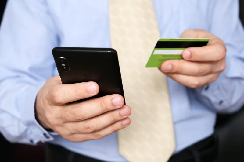 man in office clothes holding credit bank card and smartphone in hands