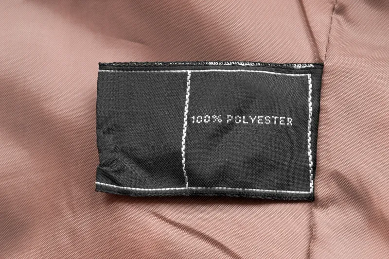 clothes label says 100 polyester on beige textile background