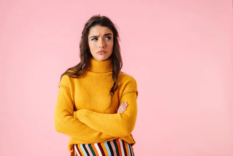 beautiful young upset woman wearing colorful clothes standing isolated over pink background