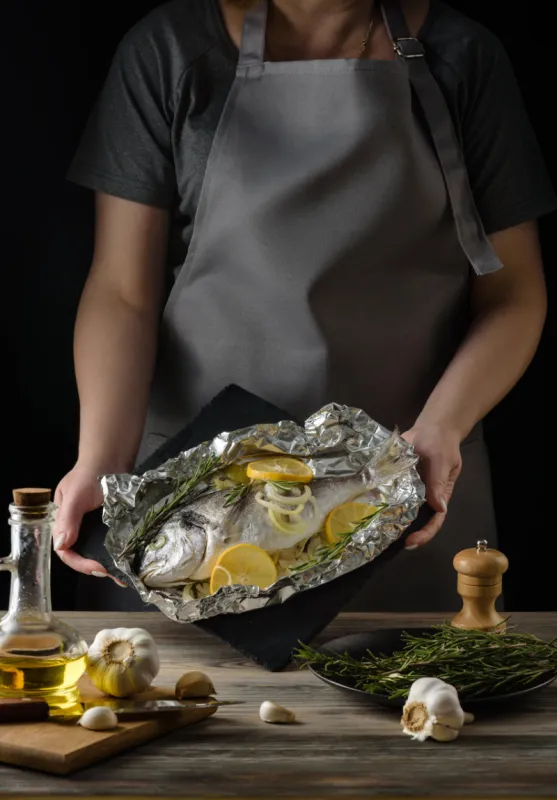 a dish with dorado fish baked in foil in the hands of the chef