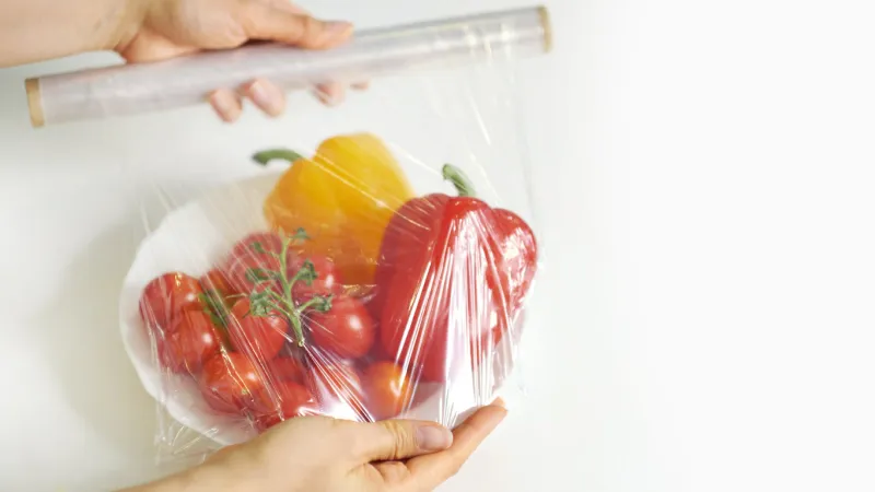 woman using food film for food storage on a white table roll of transparent polyethylene food film for packing products
