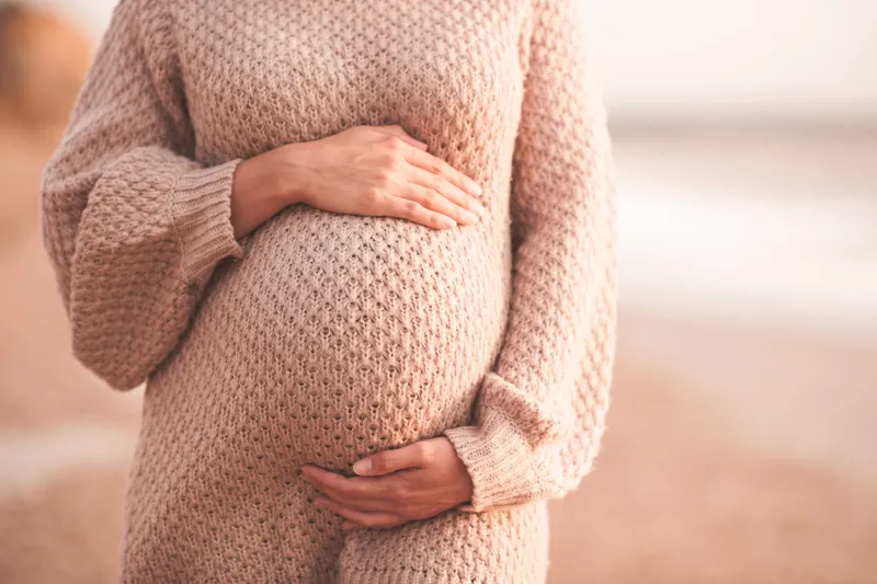 pregnant woman wearing cozy knitted sweater holding tummy with hands outdoors close up motherhood maternity heathy lifestyle