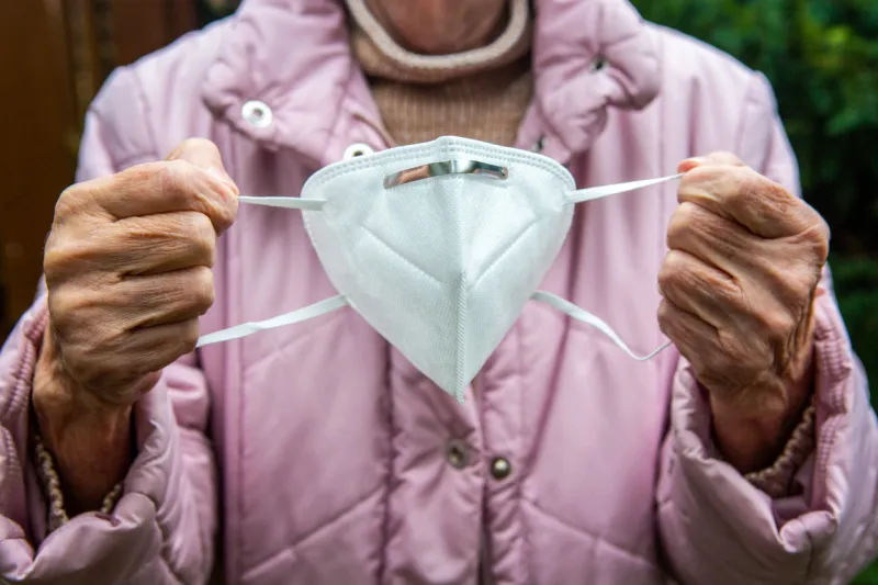 close-up of older womans hands holding face mask