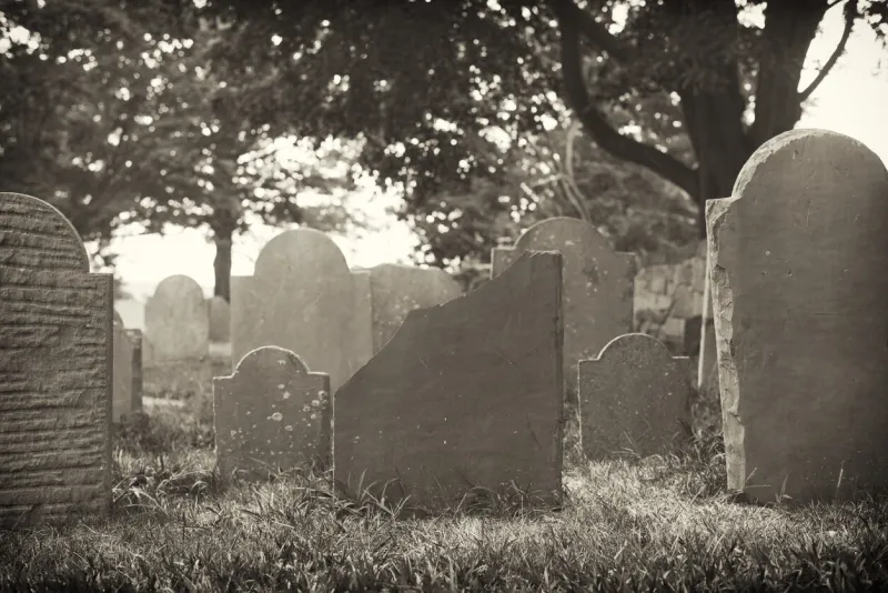 old and weathered headstones in the oldest cemetery in salem massachusetts the burying point under a old style black and white photo