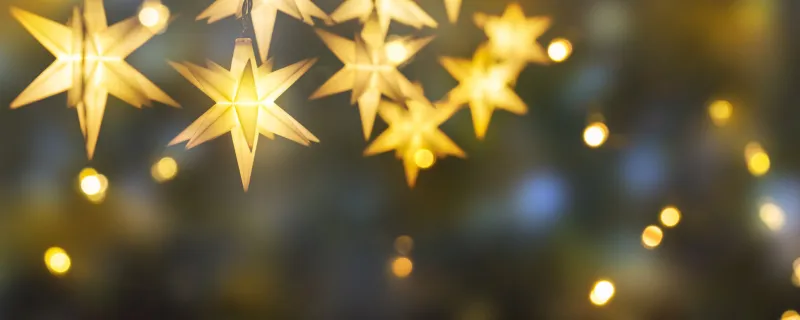 shiny christmas stars decoration on abstract background with blurred lights, illumination for celebration concept with copy space