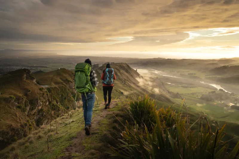 backpackers walking on a mountain during sunrise te mata peak, hawke´s bay, new zealand