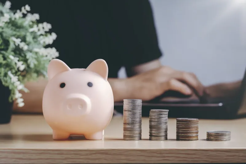 saving money wealth and financial concept asian men working at home during the crisis are calculate family income and expenses, along with pension coins and piggy banks on wooden floors