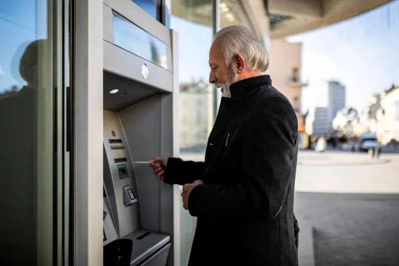 senior businessman inserting a credit card into atm