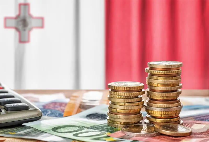 euro banknotes and coins in front of the national flag of malta