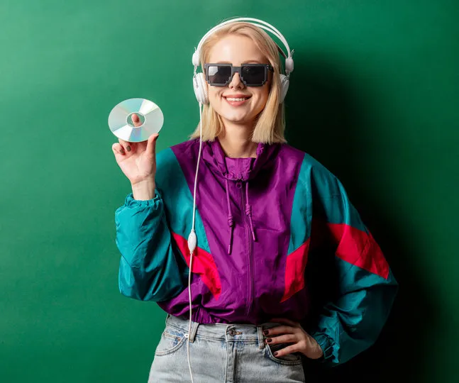 style woman in 90s punk clothes with headphones and cd on aqua menthe color background