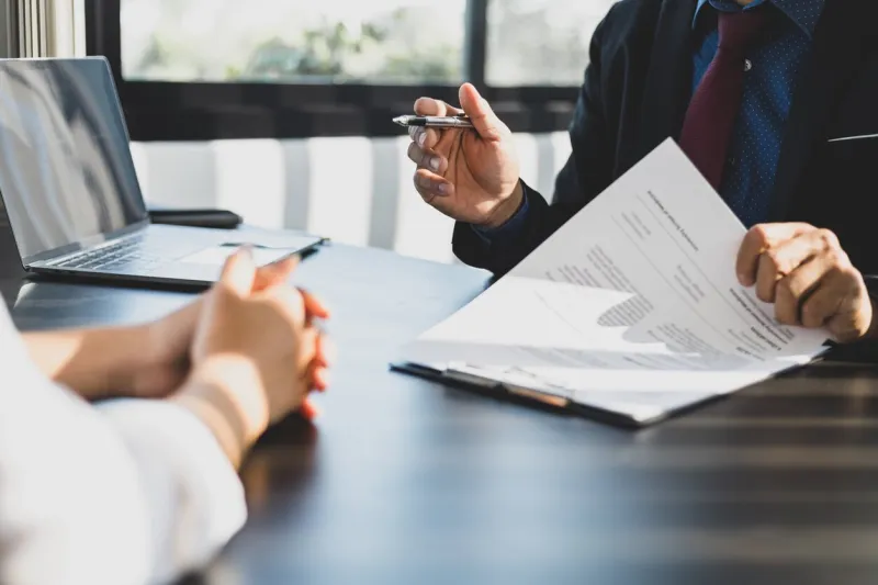 businessman in suit in his office showing an insurance policy and pointing with a pen where the policyholder must to sign insurance agent presentation and consulting insurance detail to customer
