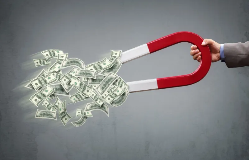 businessman attracting money with a horseshoe magnet concept for business success, strategy or greed
