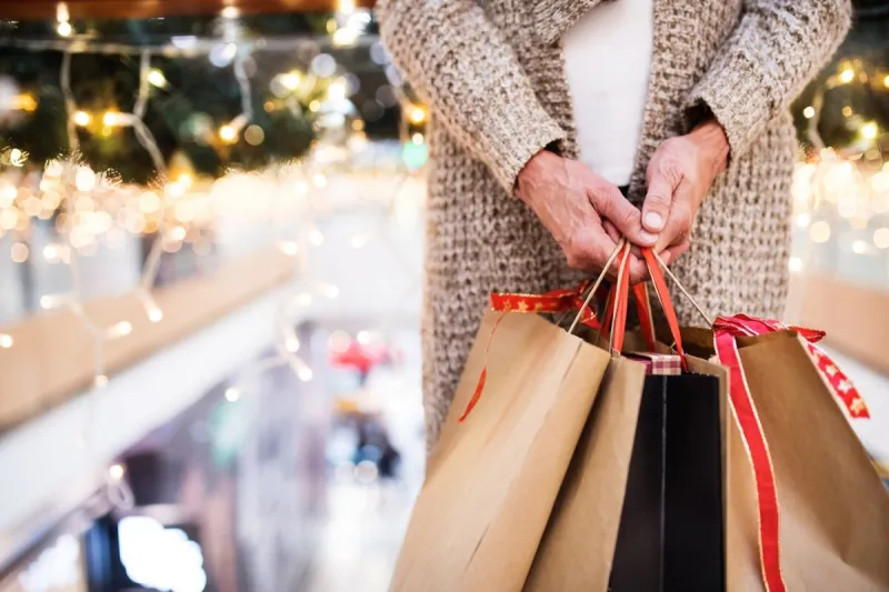 unrecognizable senior woman with paper bags doing christmas shopping shopping center at christmas time