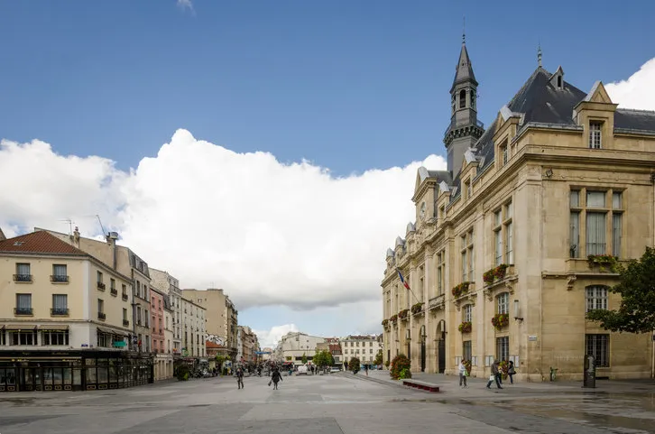 saint-denis, france - september 14, 2015  people are walking in front of the city hall which overlooks place victor hugo with rue de la republique in the distance saint-denis is a suburb of the french capital, paris