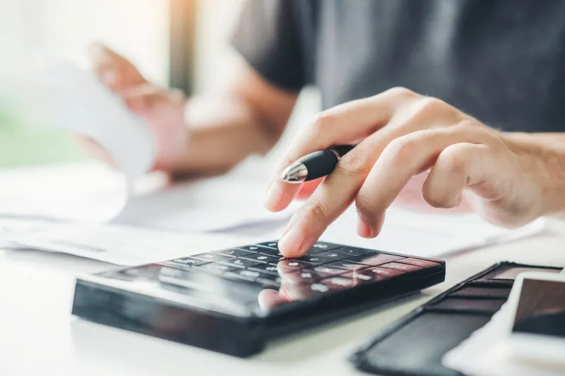 man using calculator accounting calculating cost economic bills with money stack step growing growth saving money in home , finance concept