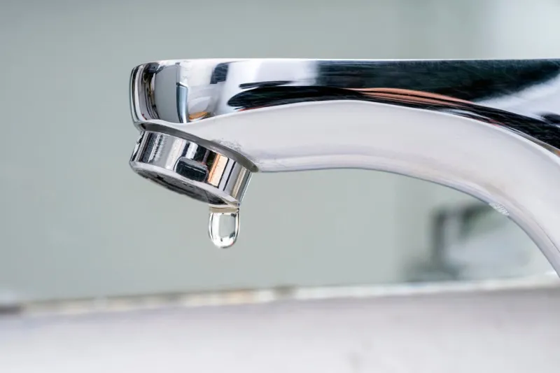 drop of water falling from faucet water supply cuts due to drought severe restrictions measures for water saving increase in prices and taxes on the water bill