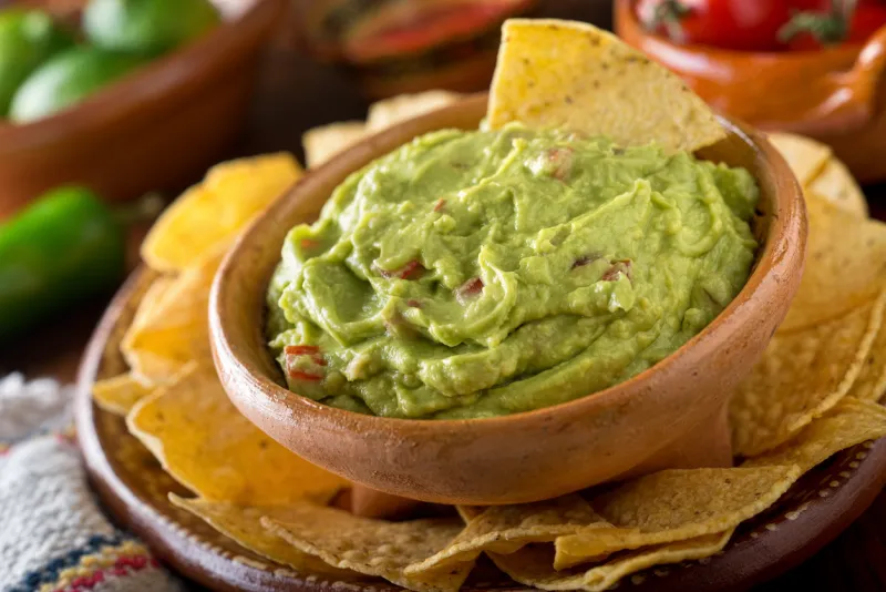 a delicious authentic mexican guacamole dip with avocado, lime, and tomato