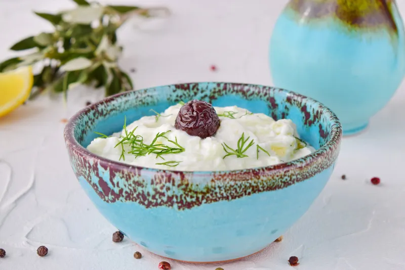 homemade greek traditional sauce tzatziki with cucumber, garlic, yogurt , olive oil and lemon in a traditional colored bowl on a white background healthy eating concept mediterranean lifestyle