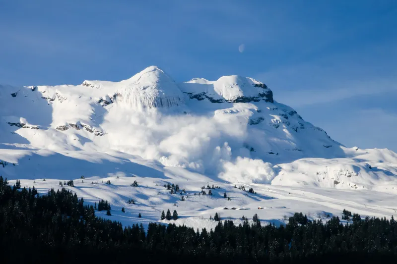 huge real avalanche in the french alps with the moon and blue sky
