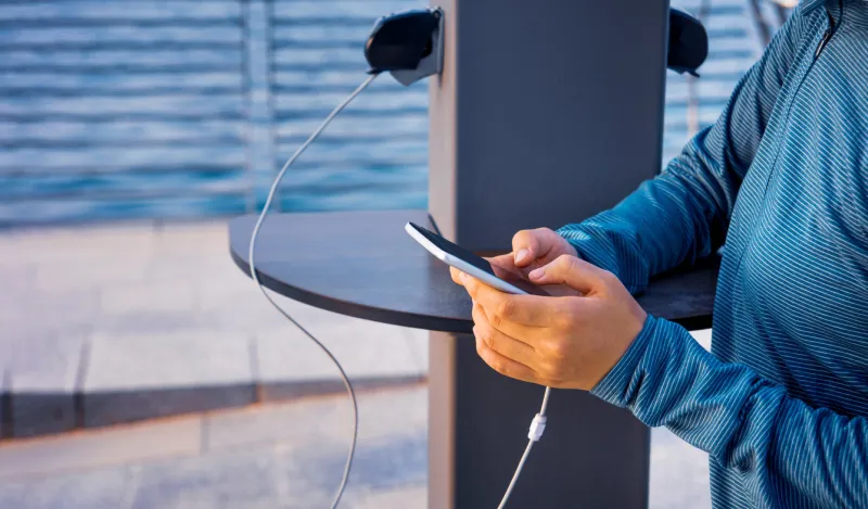 female using phone and charging on a public charger