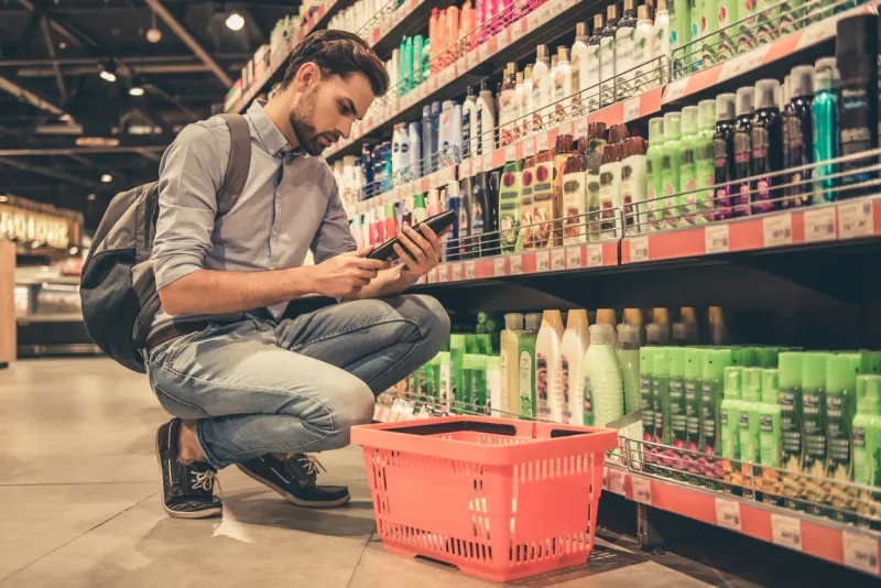 handsome man is choosing cosmetics while doing shopping at the supermarket